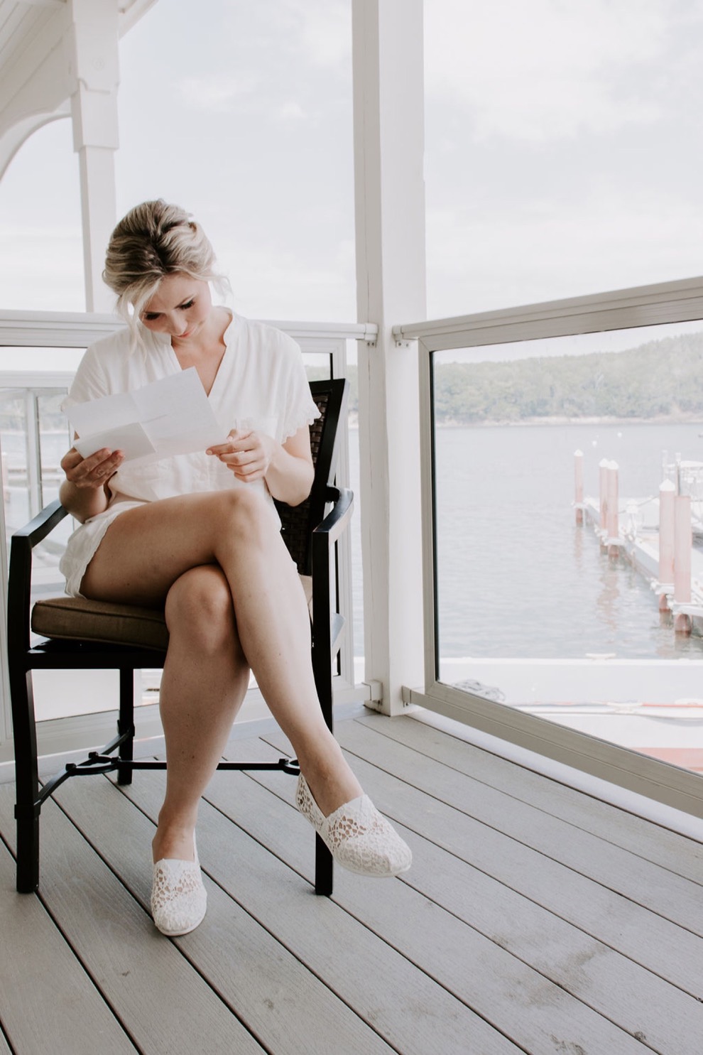 bride reading letter on balcony overlooking water