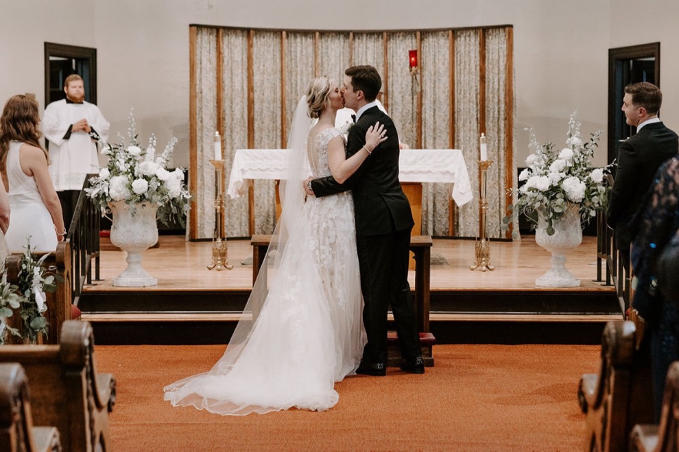 bride and groom first kiss during church wedding 