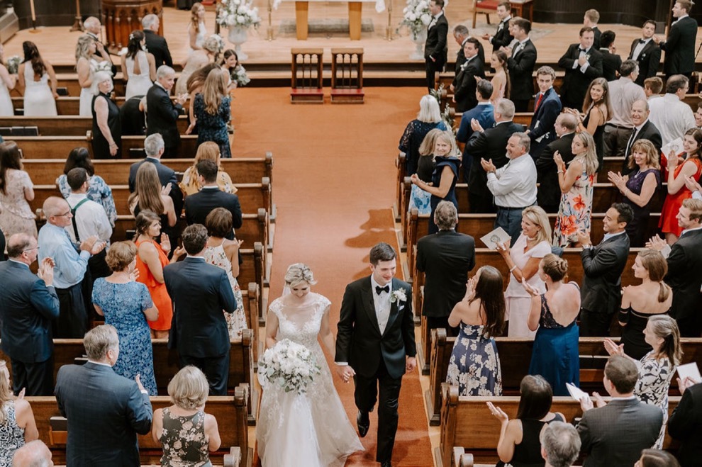 bride and groom walking down aisle together after church wedding 