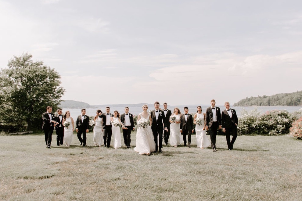 wedding party pose on grass overlooking ocean during portraits