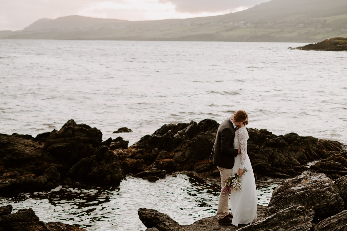 bride and groom standing on cliff's edge in Ireland