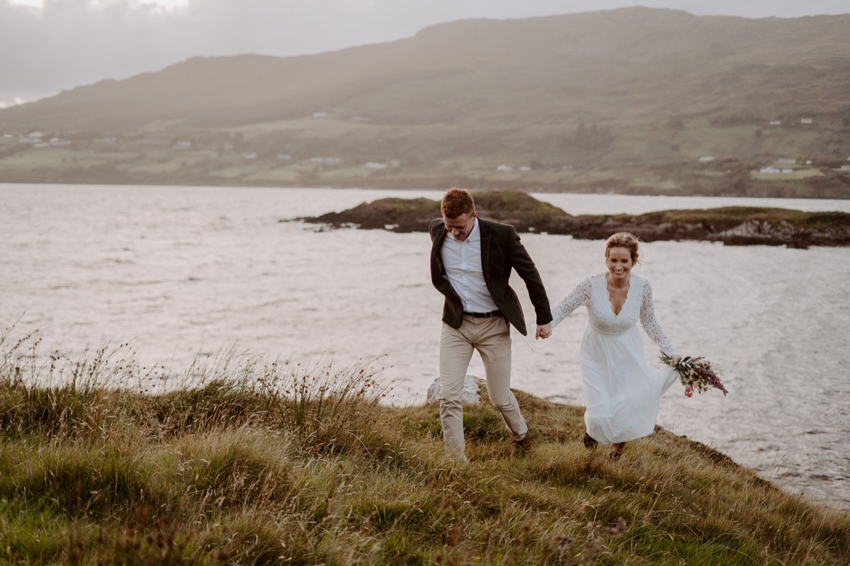 bride and groom running along Irish coast