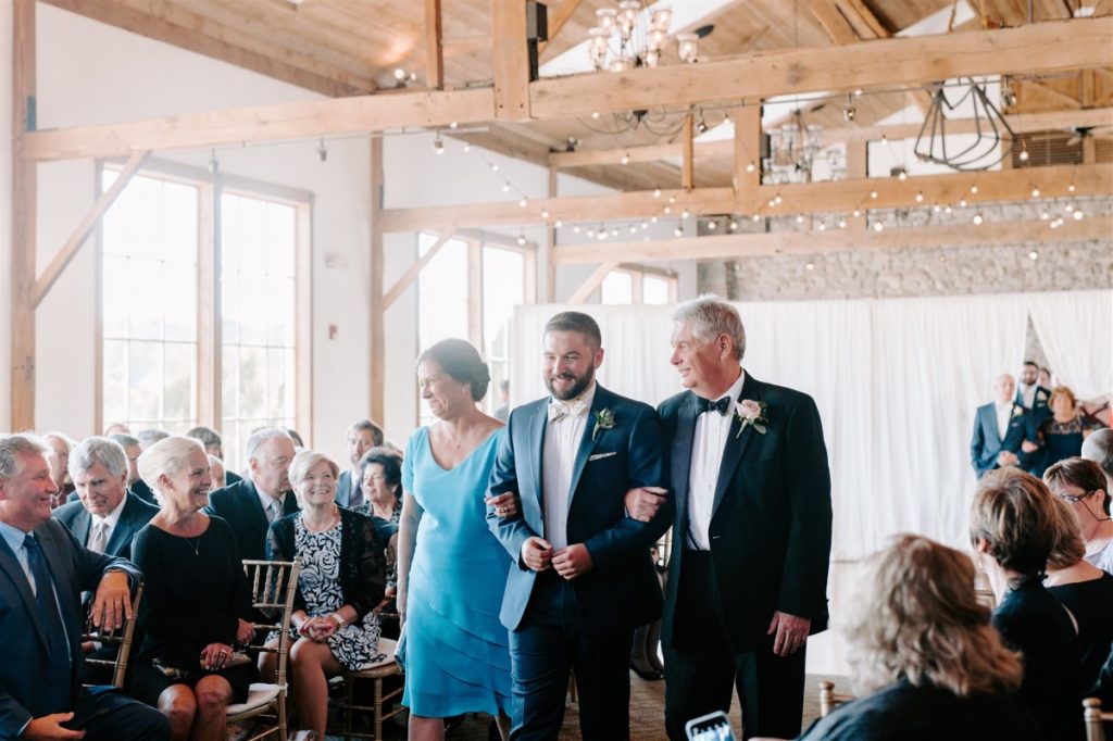 groom walks up aisle with parents