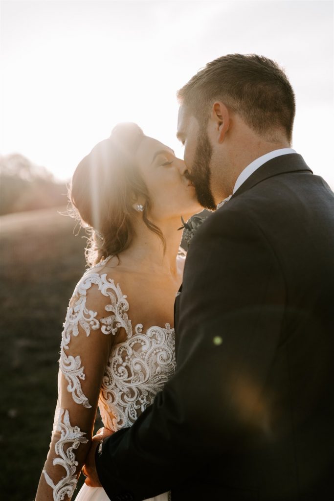 bride and groom kiss during sunset portraits