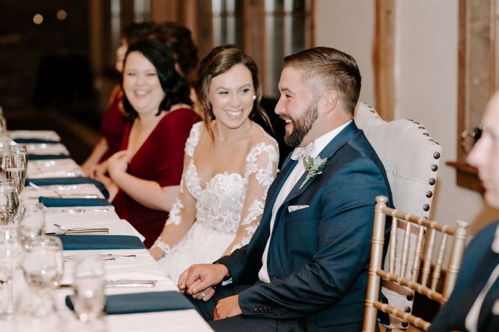 bride looks at groom and laughs during best man speech